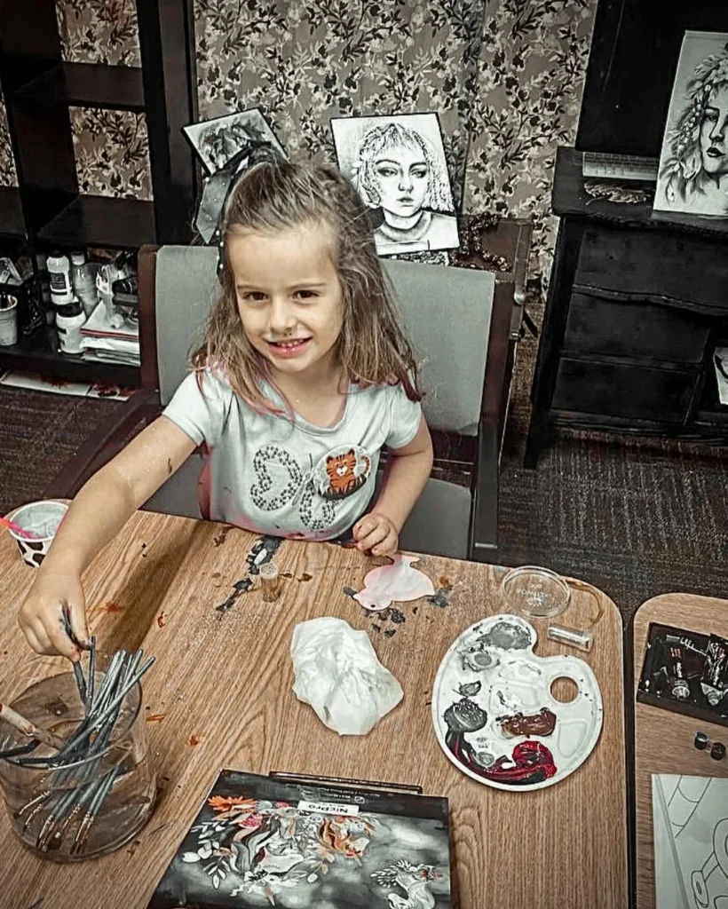 Smiling girl painting at a table during a Heart to Heart art class